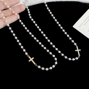 Detail of elegant pearl necklaces with gold and silver cross pendants on velvet