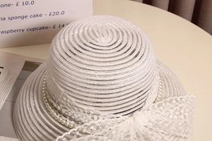 Gros plan d'un chapeau de soleil blanc avec nœud en dentelle et perles