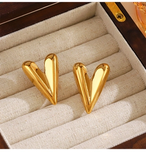 Detail shot of heart-shaped gold studs with mirror finish in a jewelry box