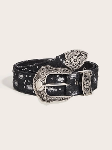 Close-up of black denim belt featuring silver carved buckle and vintage rivet details