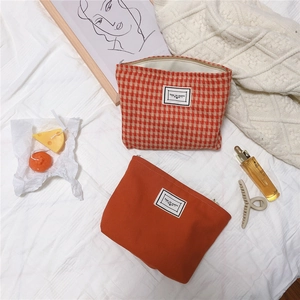 Detail of orange checkered canvas pouches with Time to Party tags on fabric surface
