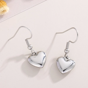 Gros plan de boucles d'oreilles cœur en argent poli sur un fond texturé doux