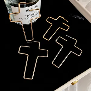 Boucles d'oreilles créoles croix évidées dorées avec tiges en argent sur velours noir