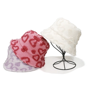 Detailed close-up of plush bucket hats in pink, lilac, and white with heart patterns