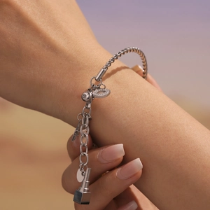 Silbernes gedrehtes Kabelarmband mit Zirkon-Anhängern und Lippenstift-Anhänger am Handgelenk