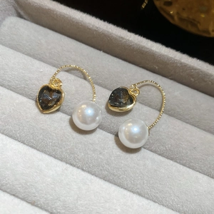 Détail macro de pierre sombre en cœur et perle blanche sur boucles dorées