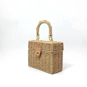 Close-up of woven straw handbag with a brown leather lock and gold hardware details