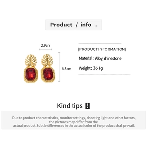 Macro view of vintage gold leaf earrings with red rectangular rhinestones and dimensions