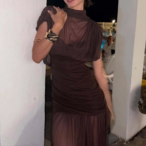 Detailed close-up of dark brown mesh dress fabric with elegant pleated texture