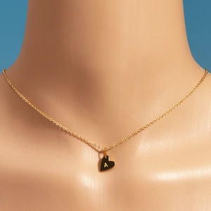Détail macro d'un pendentif cœur doré avec la lettre A sur une chaîne de collier fine
