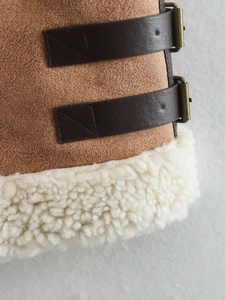 Detail of brown faux suede vest showing leather straps and white faux shearling lining