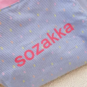 Detailed macro view of blue checkered canvas fabric with colorful dot embroidery