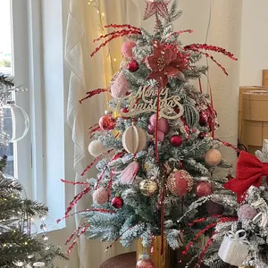 Flocked Christmas tree with red berries, ornaments, and Merry Christmas sign in gold pot