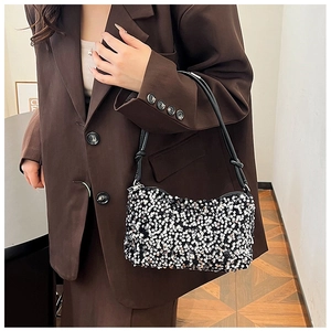 Detail of sequined shoulder bag with black strap knot design worn by a model