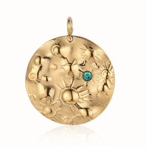 Detail of gold sun relief pendant with turquoise inlay on a white reflective background