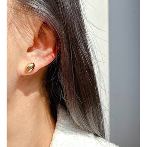 Minimalist gold-plated oval stud earrings with high-polish mirror finish on a model