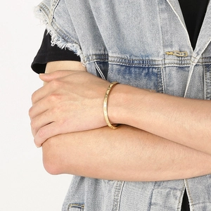 Detail of a gold C-shaped titanium steel bracelet with star and moon relief on a wrist