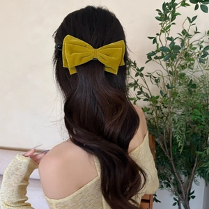 Vintage mustard yellow velvet bow hair clip worn by model on a half-up hairstyle
