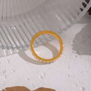 Elegant gold-plated geometric ring with paved crystals on a textured white background