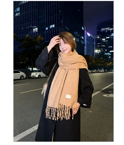 Detail shot of camel cashmere-like scarf showing soft texture and tassel design