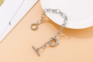 Detail of silver stainless steel chain bracelet with heart pendant and toggle clasp