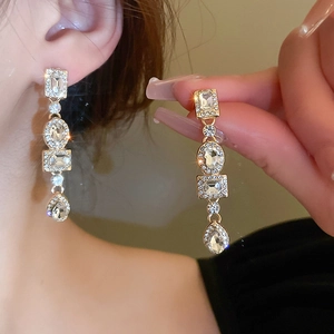 Close-up of sparkling geometric drop earrings with square and teardrop crystals