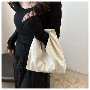 Detail of soft cream leather croissant bag with elegant pleats and minimalist handle