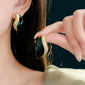 Détail de boucles d'oreilles vintage en forme de feuille noires et dorées sur un mannequin