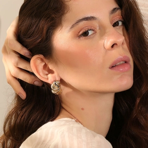 Détail de boucles d'oreilles torsadées bicolores en or et argent portées par un mannequin
