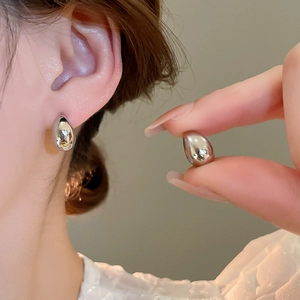 Close-up of teardrop earrings in polished silver finish worn by a model for detail