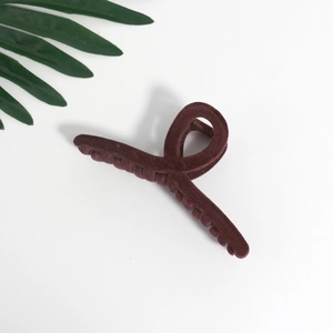 Macro detail of dark red velvet hair claw clip with cross design and metal spring