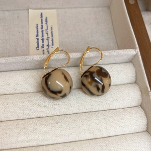 Close-up of marble pattern spherical drop earrings in a vintage striped jewelry box