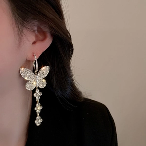 Close-up of model wearing luxury butterfly tassel earrings with sparkling crystals and pearls
