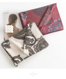 Close-up of paisley print wool scarves in red and beige with elegant fringed edges