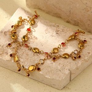 Detailed close-up of 18K gold-plated necklace with red and clear crystal water-drop charms