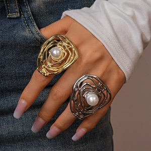 Detail of irregular hollow gold and silver rings with pearls worn on model hand