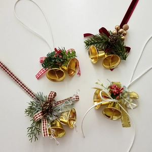Golden Christmas bell ornaments with pine cones, berries, and ribbons on a white background