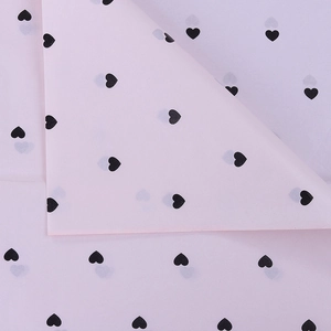 Close-up of pink tissue paper with black heart patterns for floral bouquet packaging