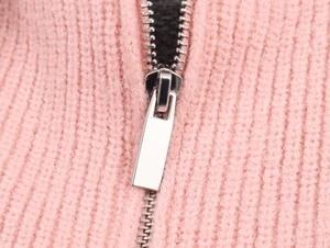 Macro shot of silver metal zipper on pink ribbed knit cardigan showing fabric texture