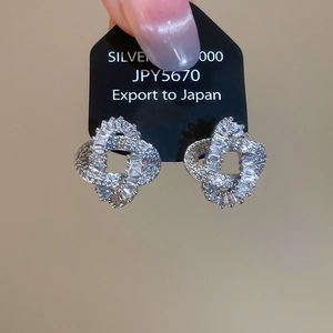 Macro view of silver four-leaf clover earrings with sparkling pavé cubic zirconia