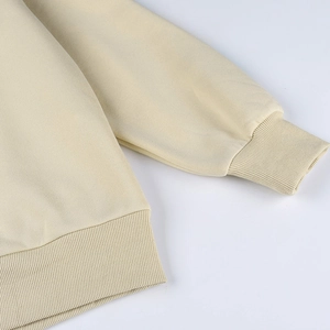 Gros plan des poignets et de l'ourlet côtelés du sweat-shirt beige montrant le tissu