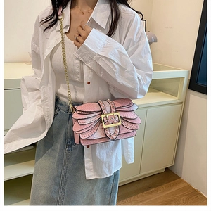 Pink snakeskin shoulder bag with gold chain and pearls shown on a model outfit