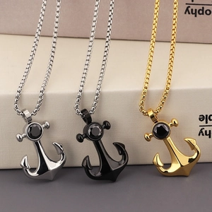 Three anchor necklaces in silver, black and gold with black stones on a book background