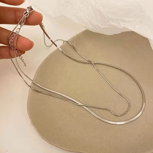 Double-layered stainless steel snake chain necklace with adjustable clasp on a ceramic tray