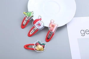 Close-up of four glittery Christmas hair clips featuring a tree, Santa, sock and bell
