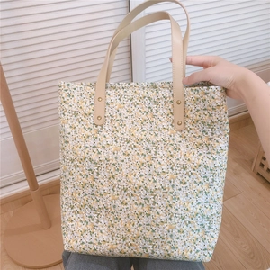 Detail of floral tote bag with brown faux leather handles and gold rivet reinforcement