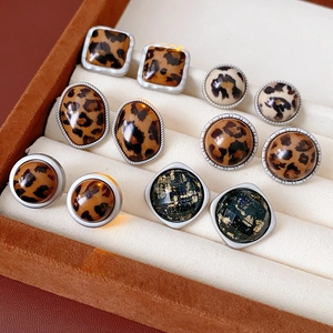 Vue détaillée de boucles d'oreilles léopard et bleu marine dans un coffret en velours brun