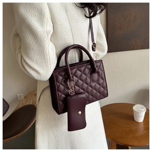 Close-up of wine red quilted handbag with matching mini coin purse and leather texture
