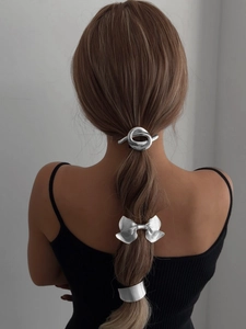 Detail view of silver bow hair clips and ponytail cuffs on a model's ponytail