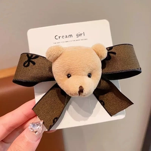 Detail of cute plush bear and brown fabric bow hairclip on a branded display card